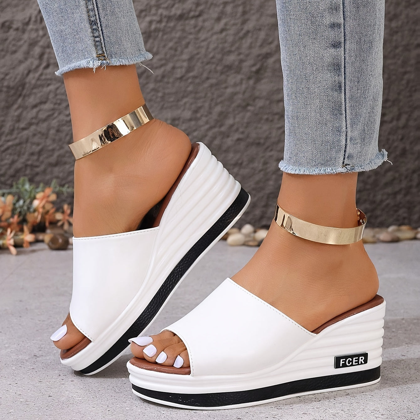 Diseño slip-on de punta abierta en blanco sólido, realzado con un elegante acento dorado en el tobillo. Con suela gruesa de poliuretano para un soporte duradero, son perfectas para un estilo casual y sofisticado.